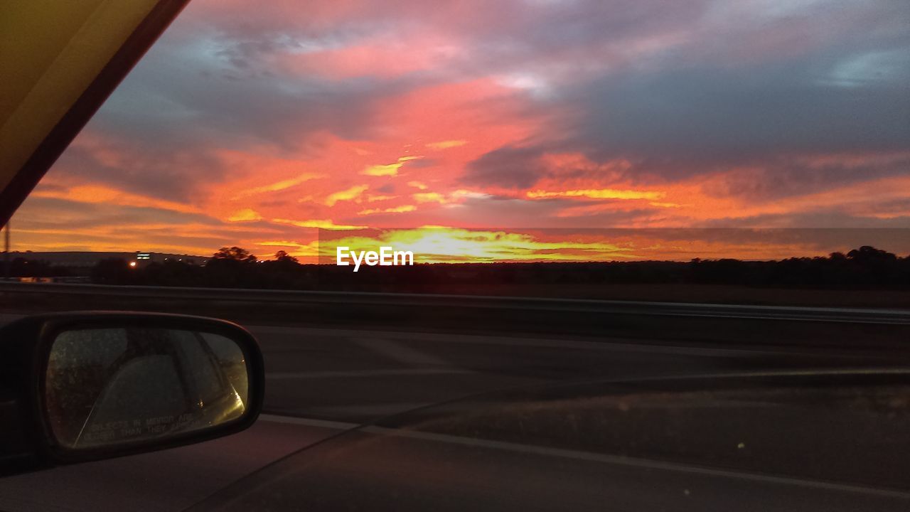 CAR ON ROAD AGAINST SKY DURING SUNSET SEEN FROM WINDSHIELD