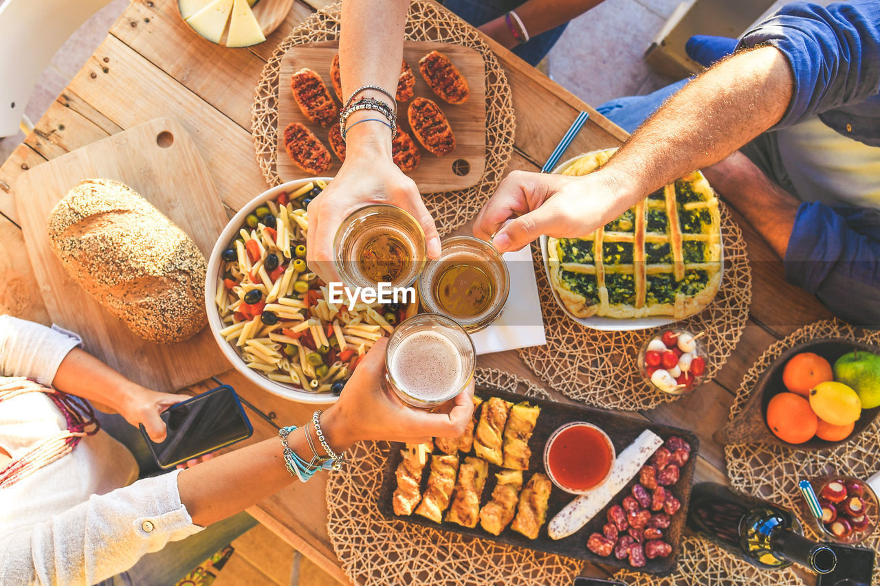 High angle view of people toasting beer on table