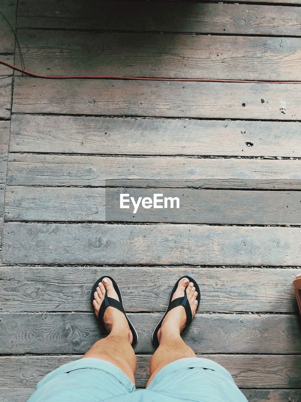 Low section of person standing on wooden boardwalk