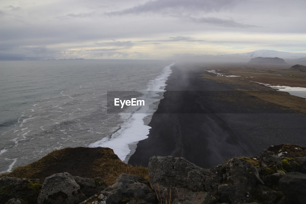 View to endless ocean black volcanic sand beach from dyrholaey cape viewpoint, vik, south iceland.