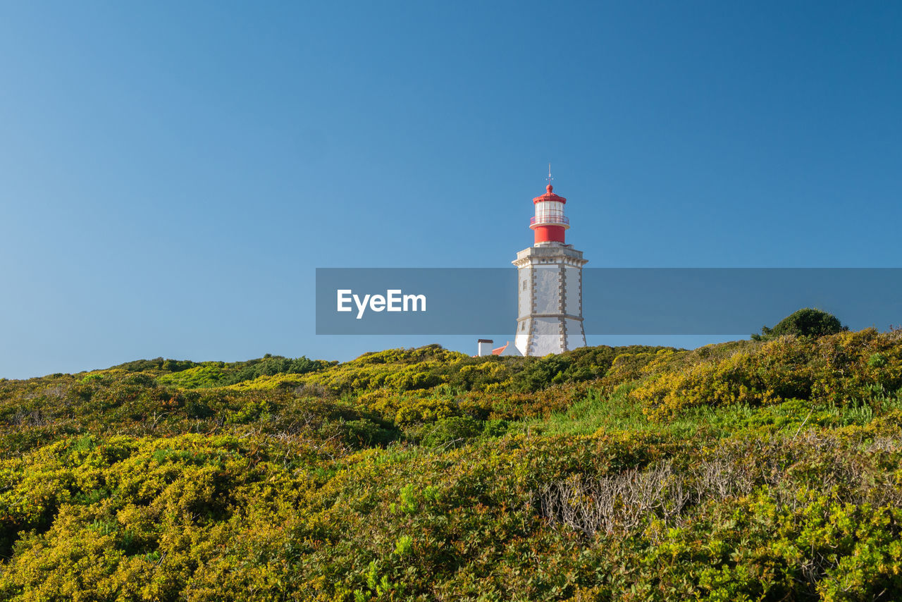 Low angle view of lighthouse by building against sky