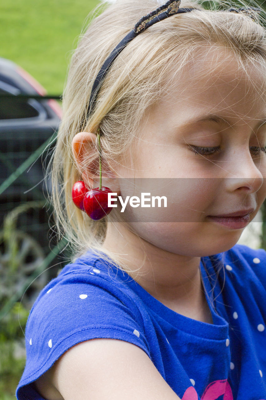 Close-up of cute girl with cherry on ear