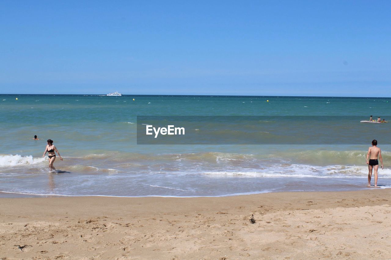 MAN ON BEACH AGAINST SKY