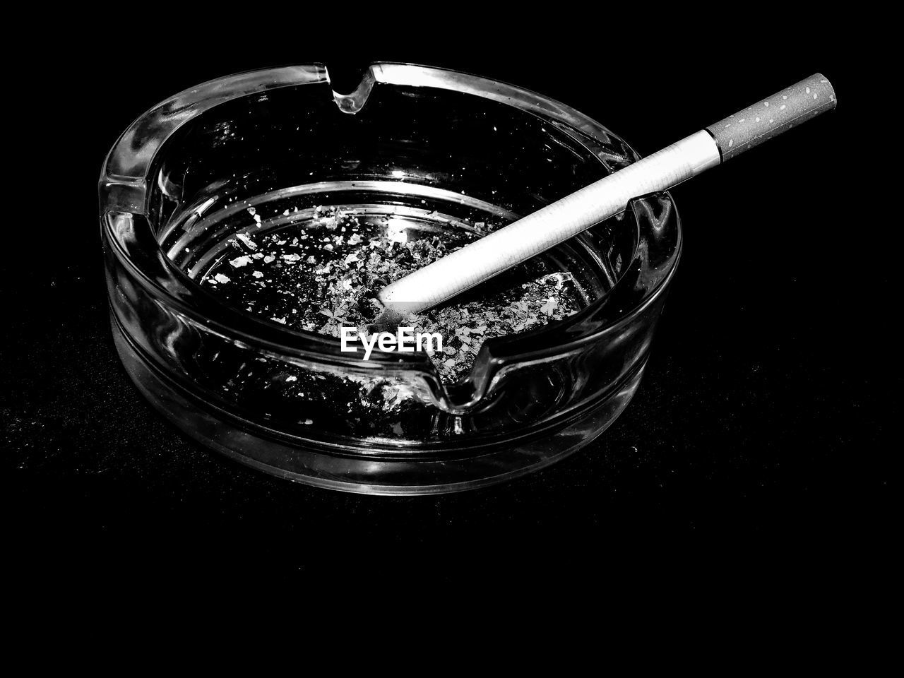 Close-up of burnt cigarette in ashtray on black background