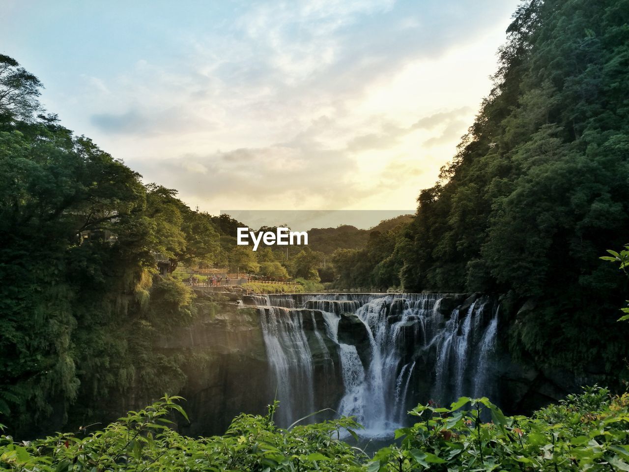 Scenic view of waterfall in forest against sky