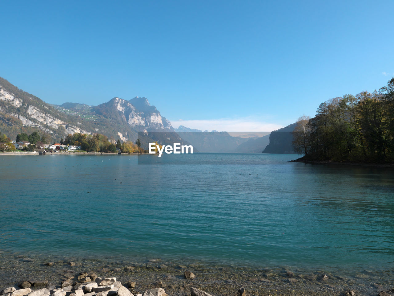 Scenic view of lake and mountains against clear blue sky