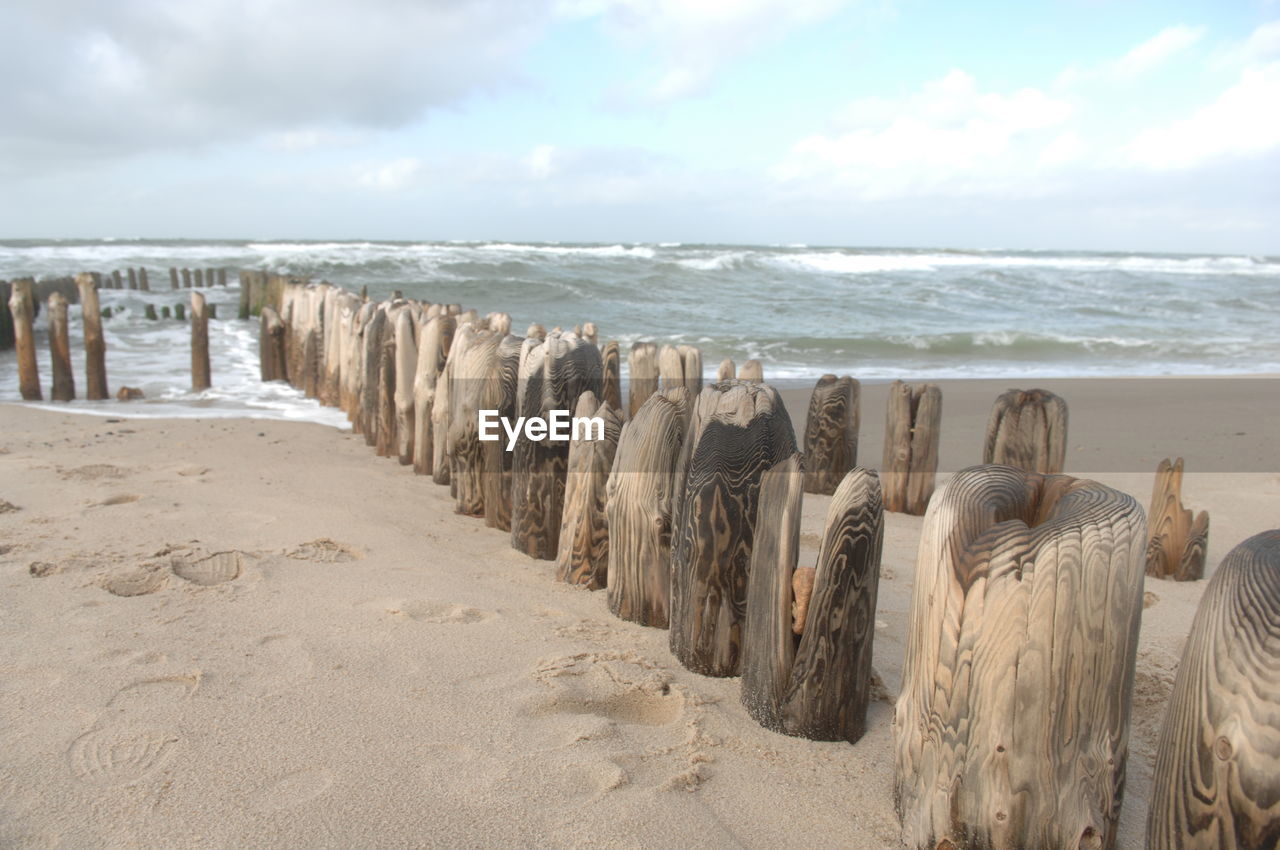 PANORAMIC SHOT OF WOODEN POSTS ON BEACH AGAINST SKY