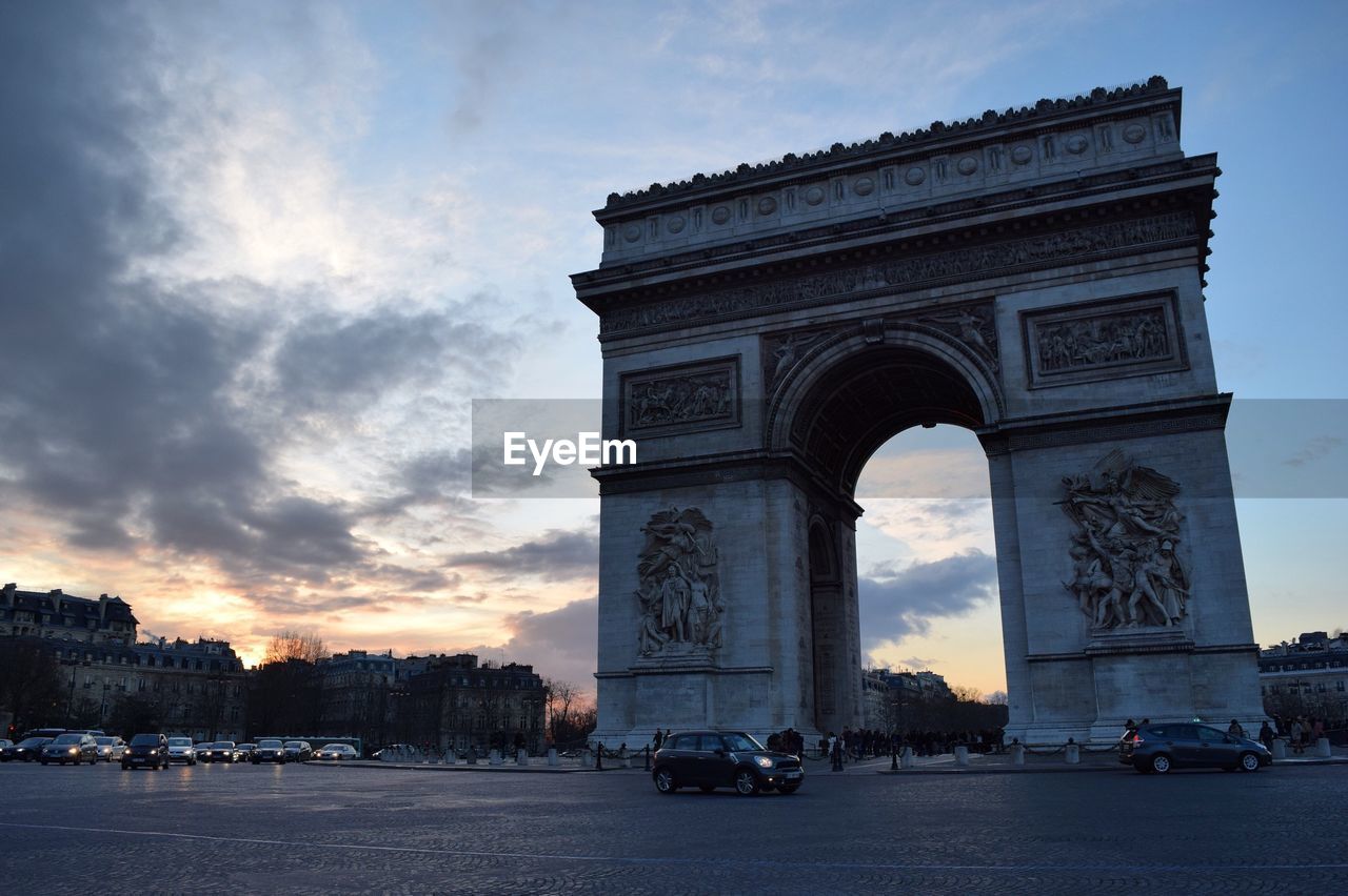 Arc de triomphe by road against sky during sunset in city