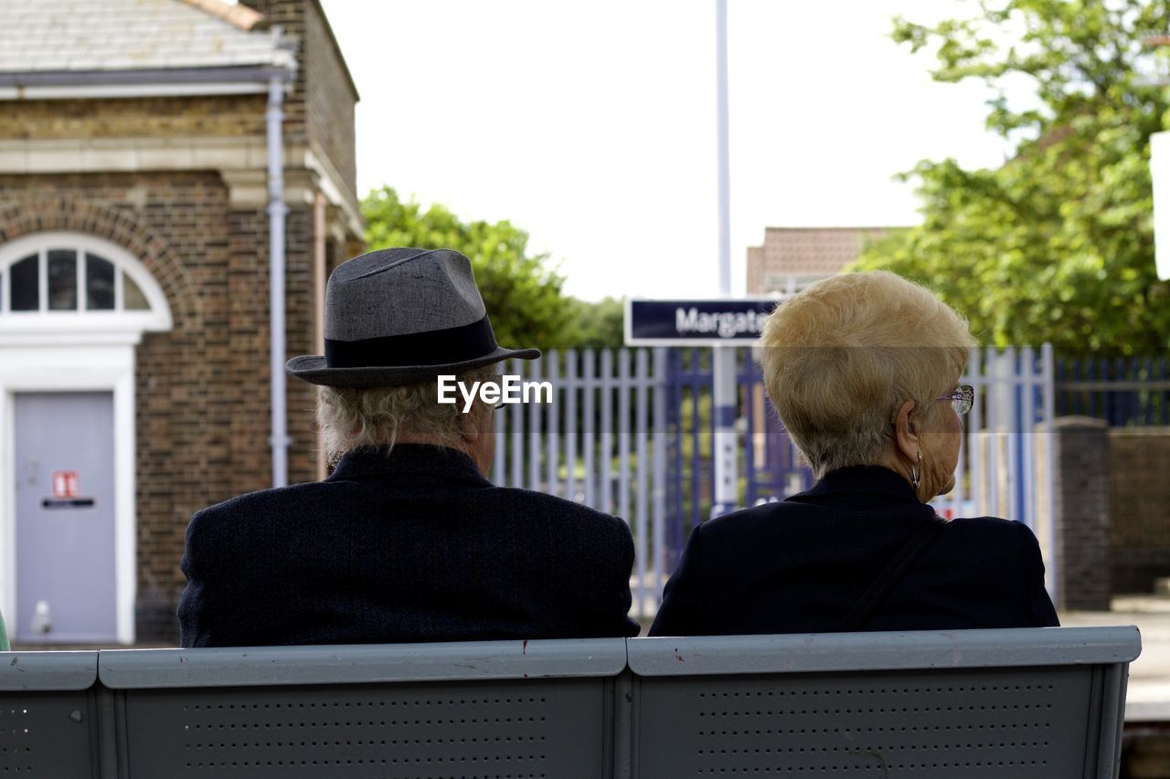 Rear view of senior man and woman sitting on bench