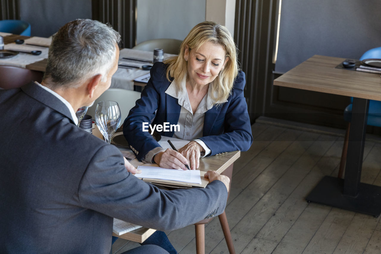 Client signing contract at meeting with businessman in restaurant