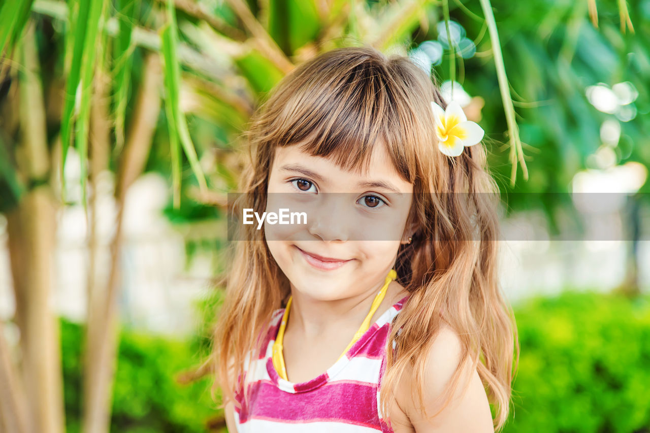 Portrait of young woman standing against plants