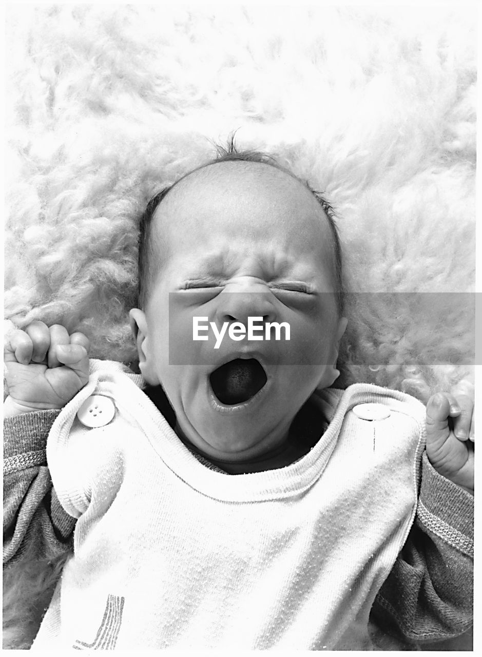 High angle view of cute new born baby yawning on bed