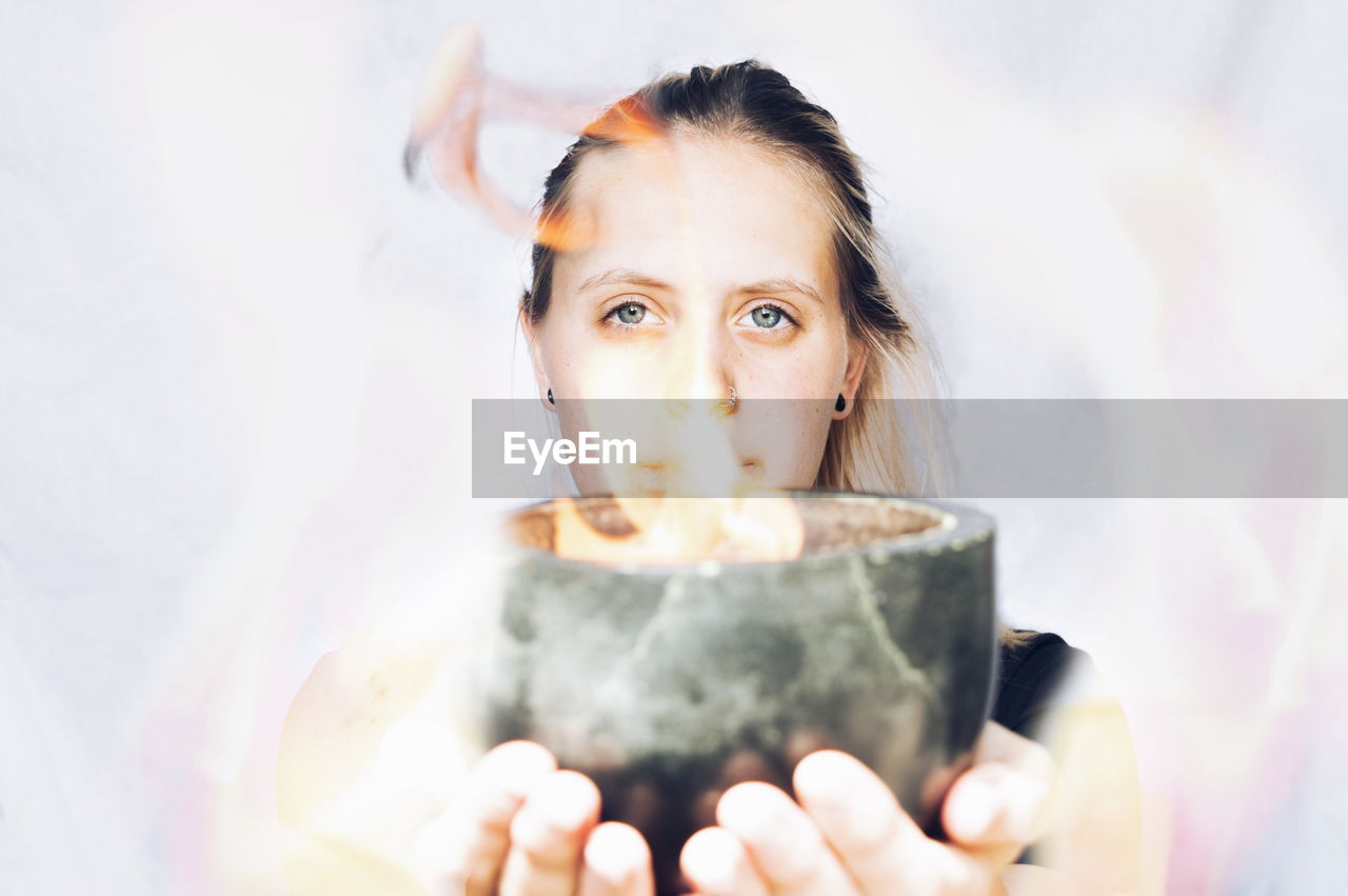 Digital composite image of woman holding fire in bowl