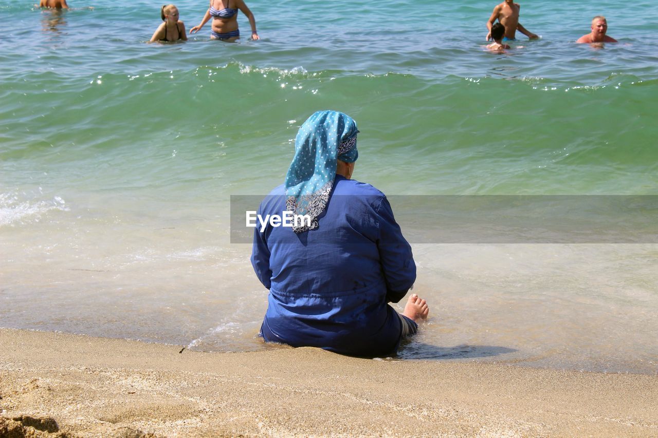 REAR VIEW OF MAN AND WOMAN STANDING IN WATER