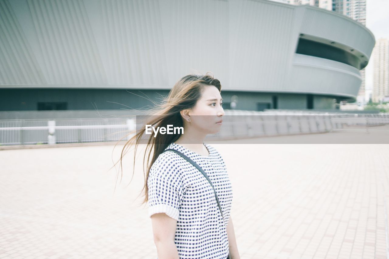 Beautiful woman standing by building in city