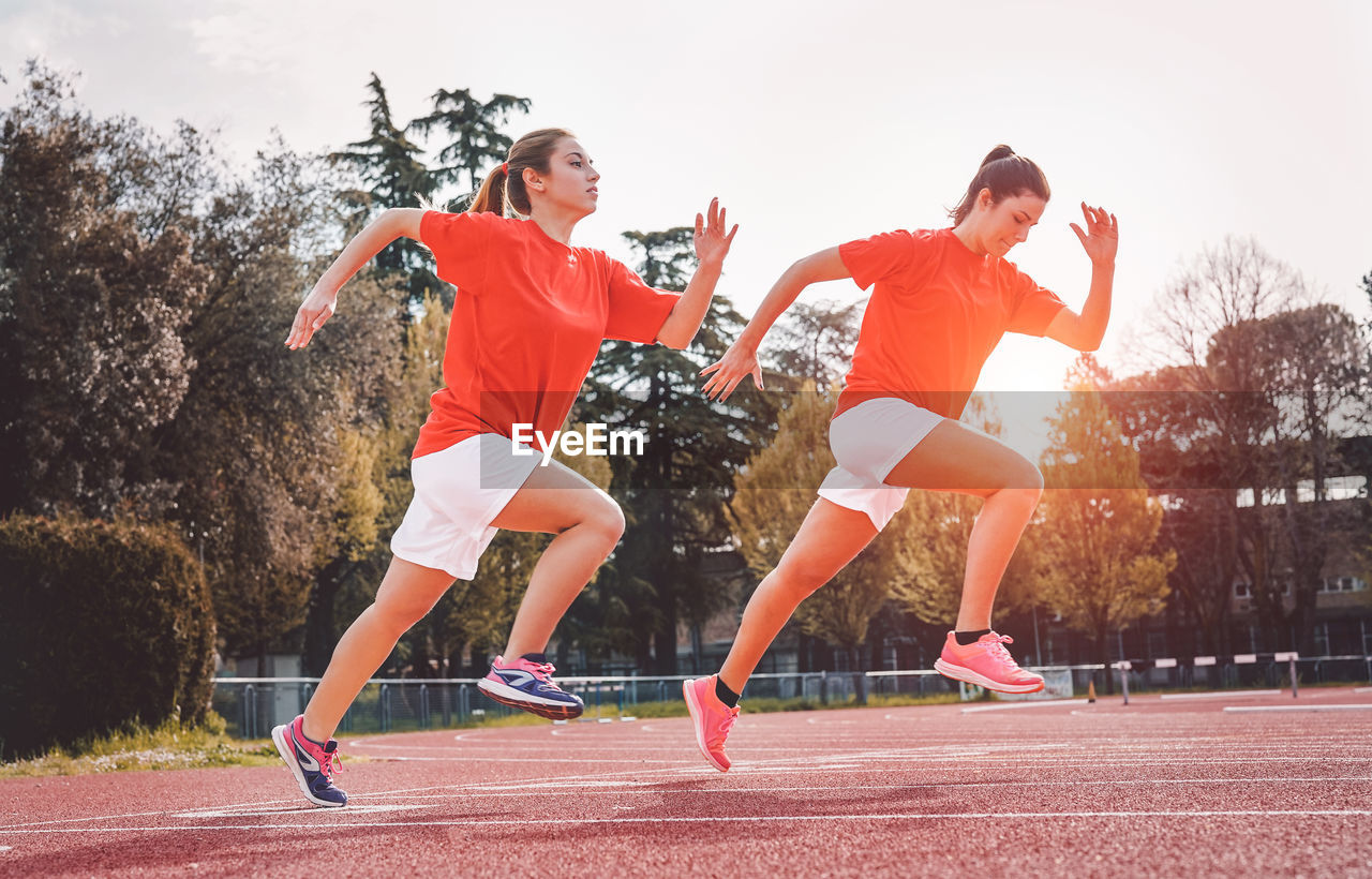 Women running on track against clear sky