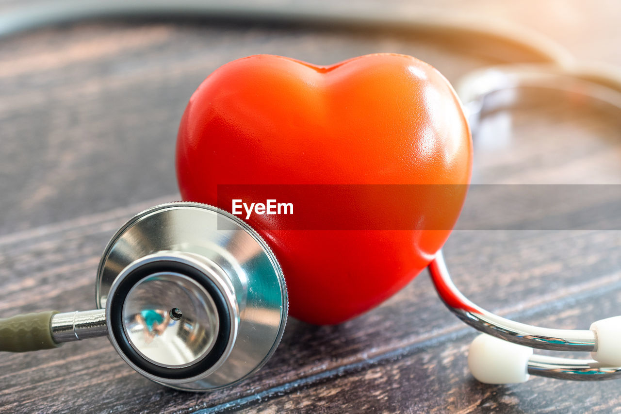 Close-up of stethoscope and heart shape object on table