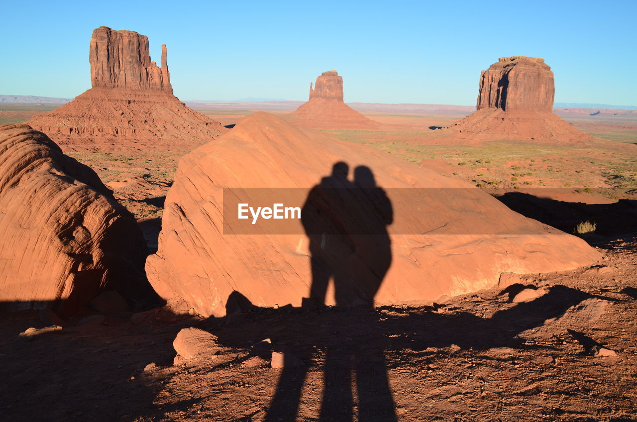 Shadow of couple on rock at field in monument valley