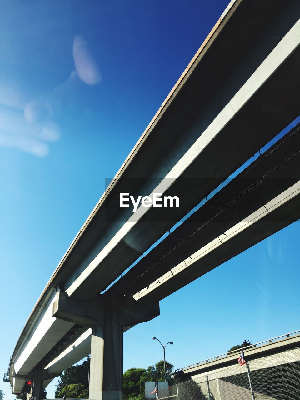 LOW ANGLE VIEW OF BRIDGE AGAINST BLUE SKY IN CITY