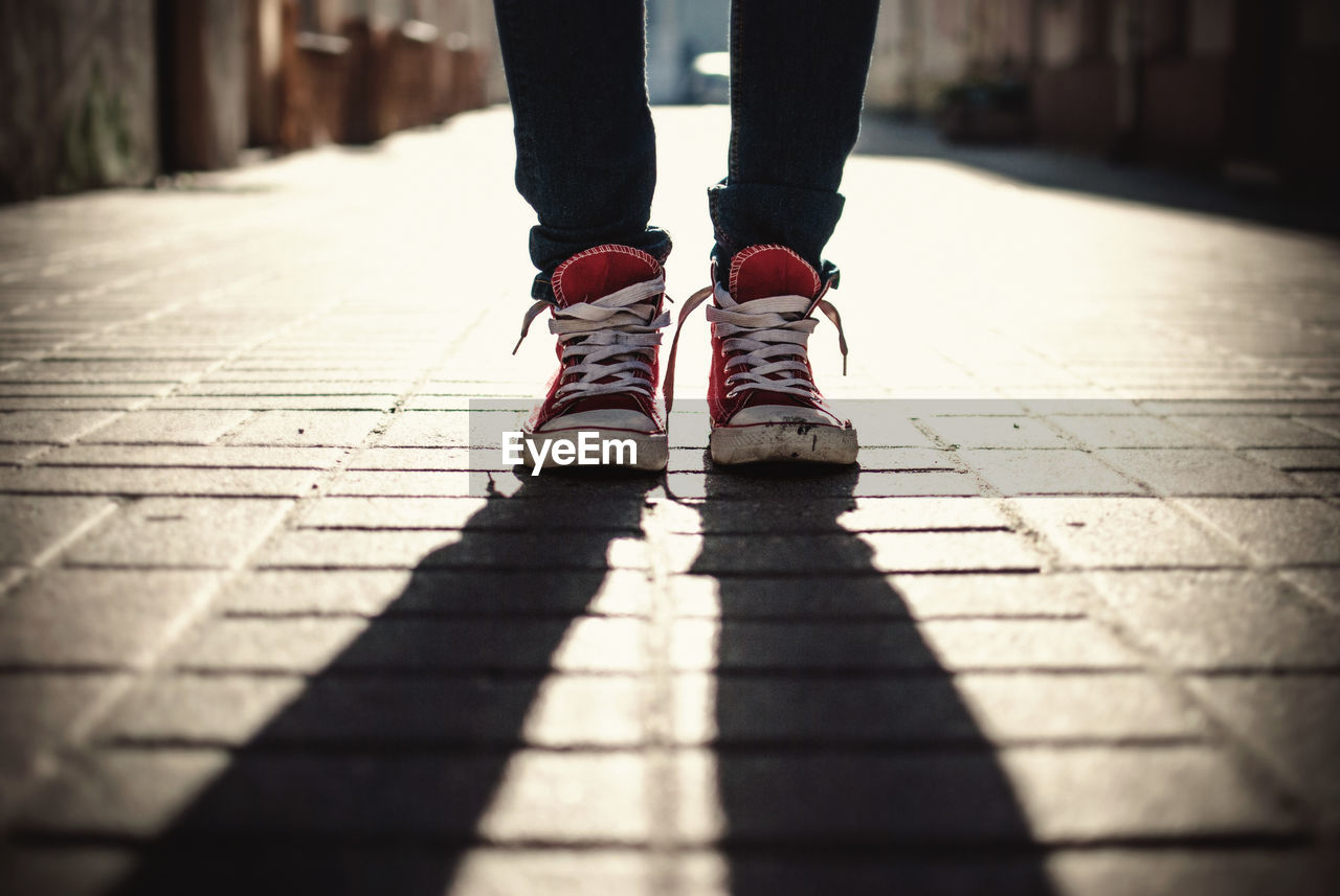 Low section of man standing with shadow on footpath