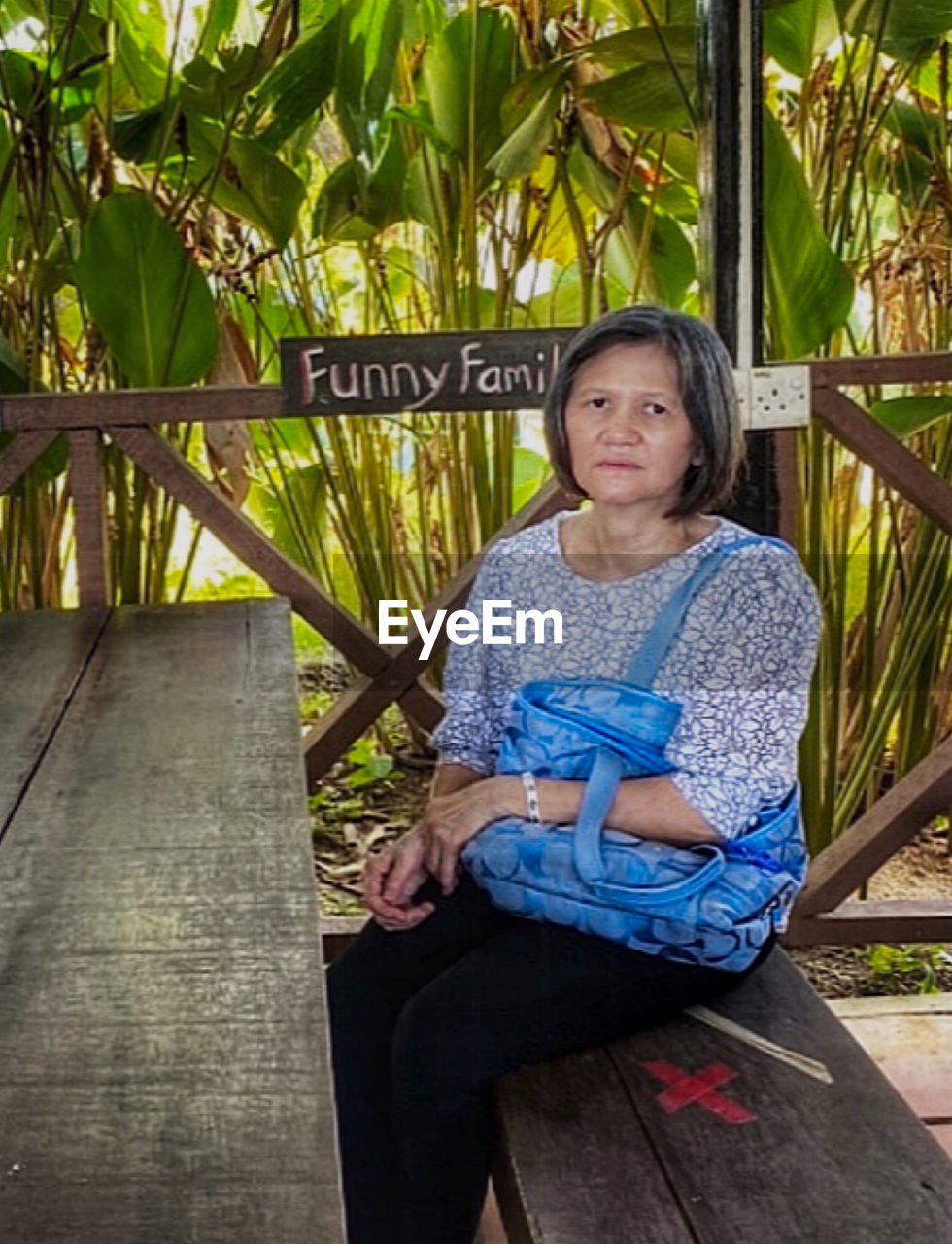 one person, sitting, women, leisure activity, plant, full length, casual clothing, child, lifestyles, front view, nature, portrait, female, tree, relaxation, adult, looking at camera, three quarter length, day, wood, outdoors, childhood, looking, palm tree, seat, tropical climate, vacation, smiling, clothing, flower, leaf, emotion