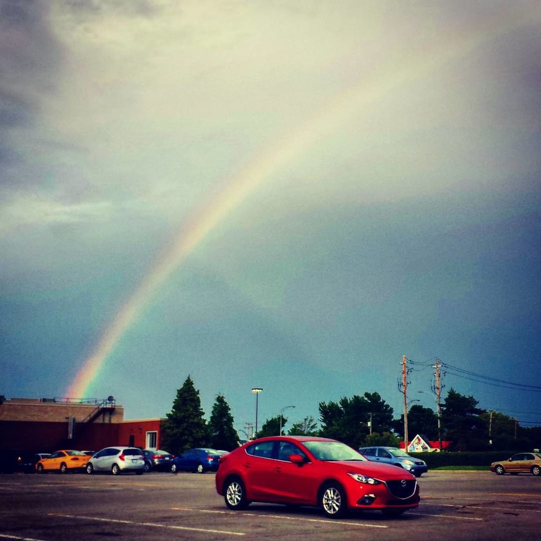 VIEW OF RAINBOW OVER CARS ON ROAD AGAINST SKY