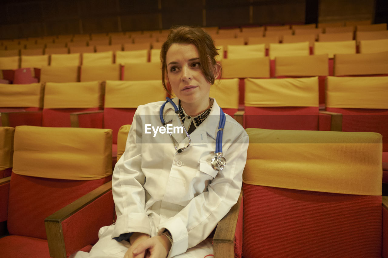 Thoughtful doctor with stethoscope sitting on chair