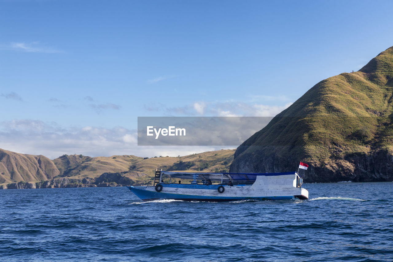 PEOPLE ON BOAT IN SEA AGAINST SKY