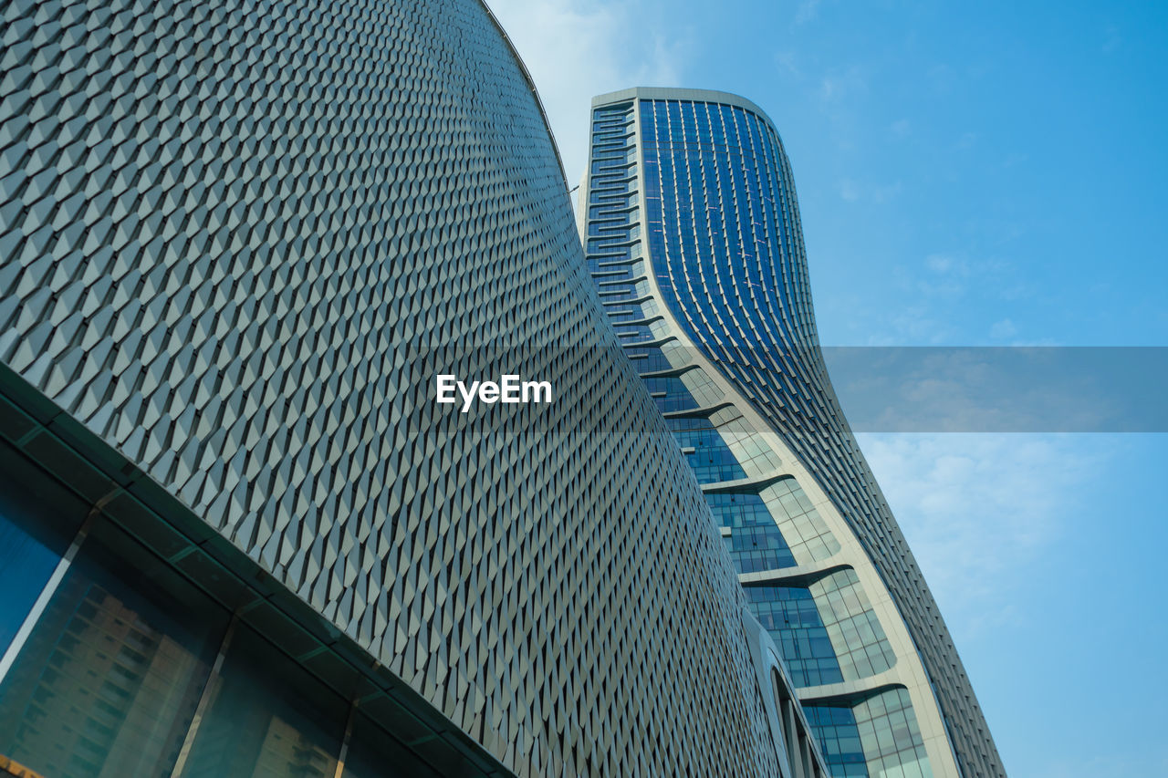 LOW ANGLE VIEW OF MODERN GLASS BUILDING AGAINST SKY