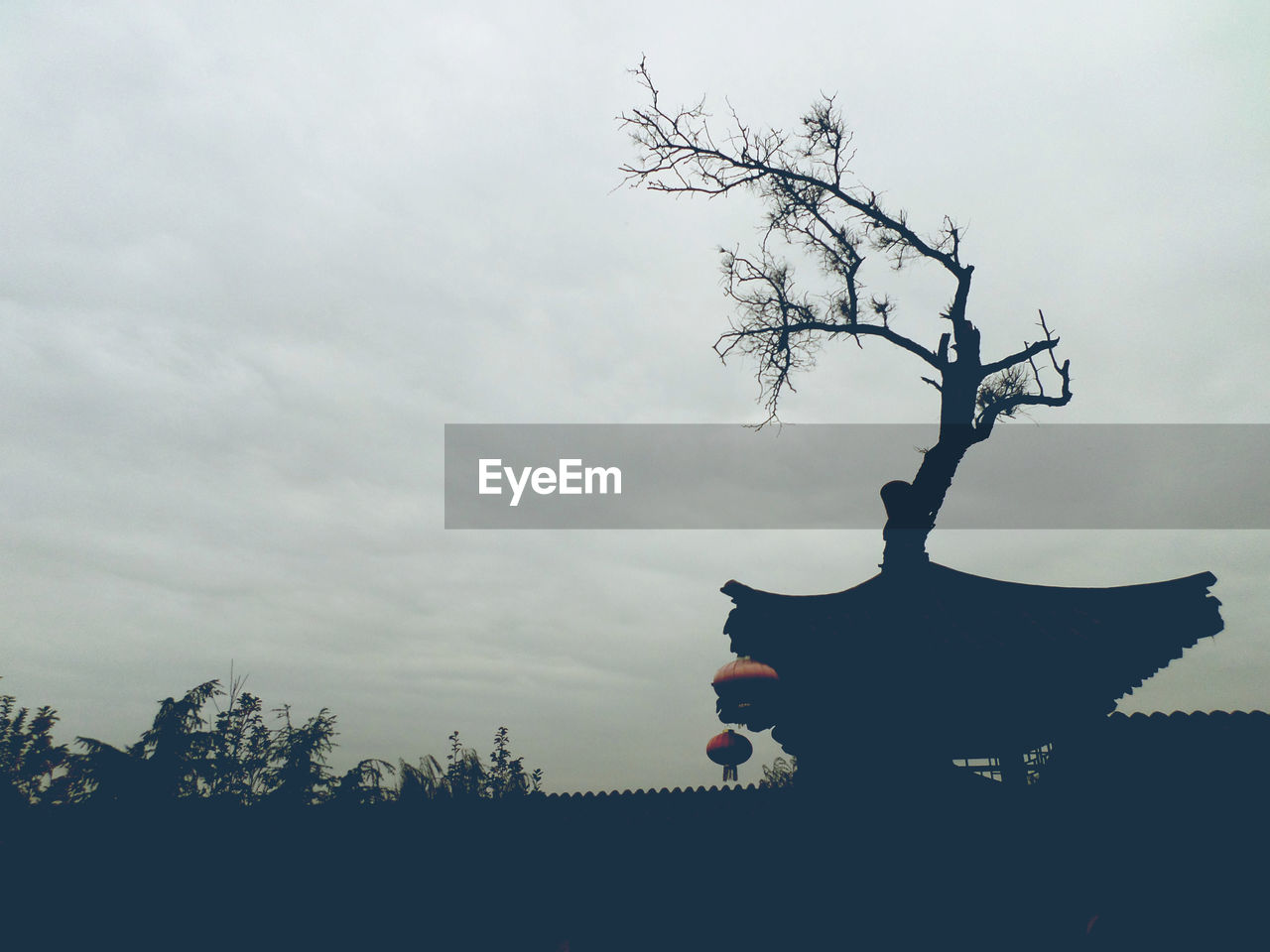 Low angle view of silhouette temple and trees against cloudy sky