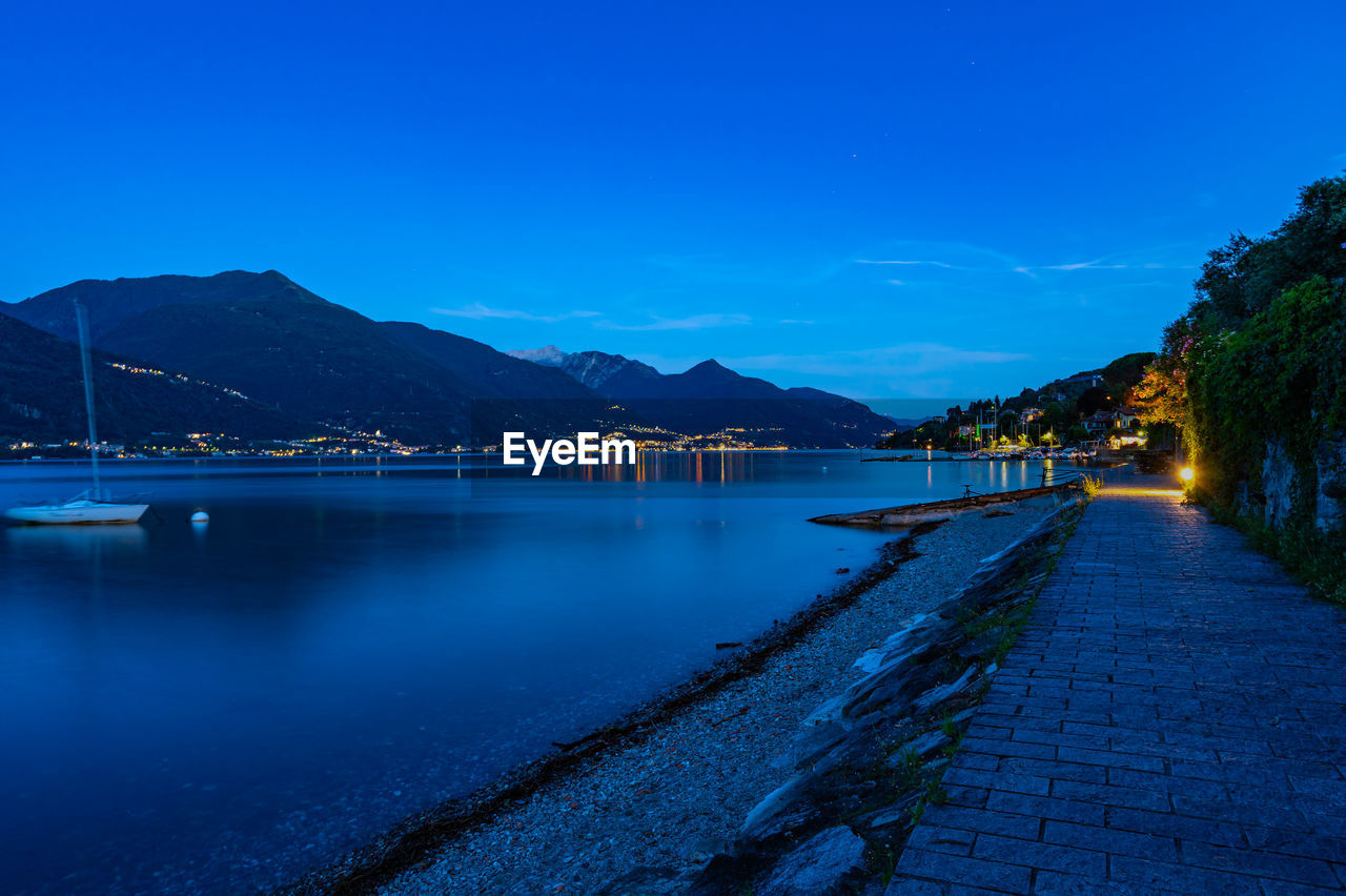 The town of pianello del lario, on lake como, and the promenade along the lake, at dusk. 