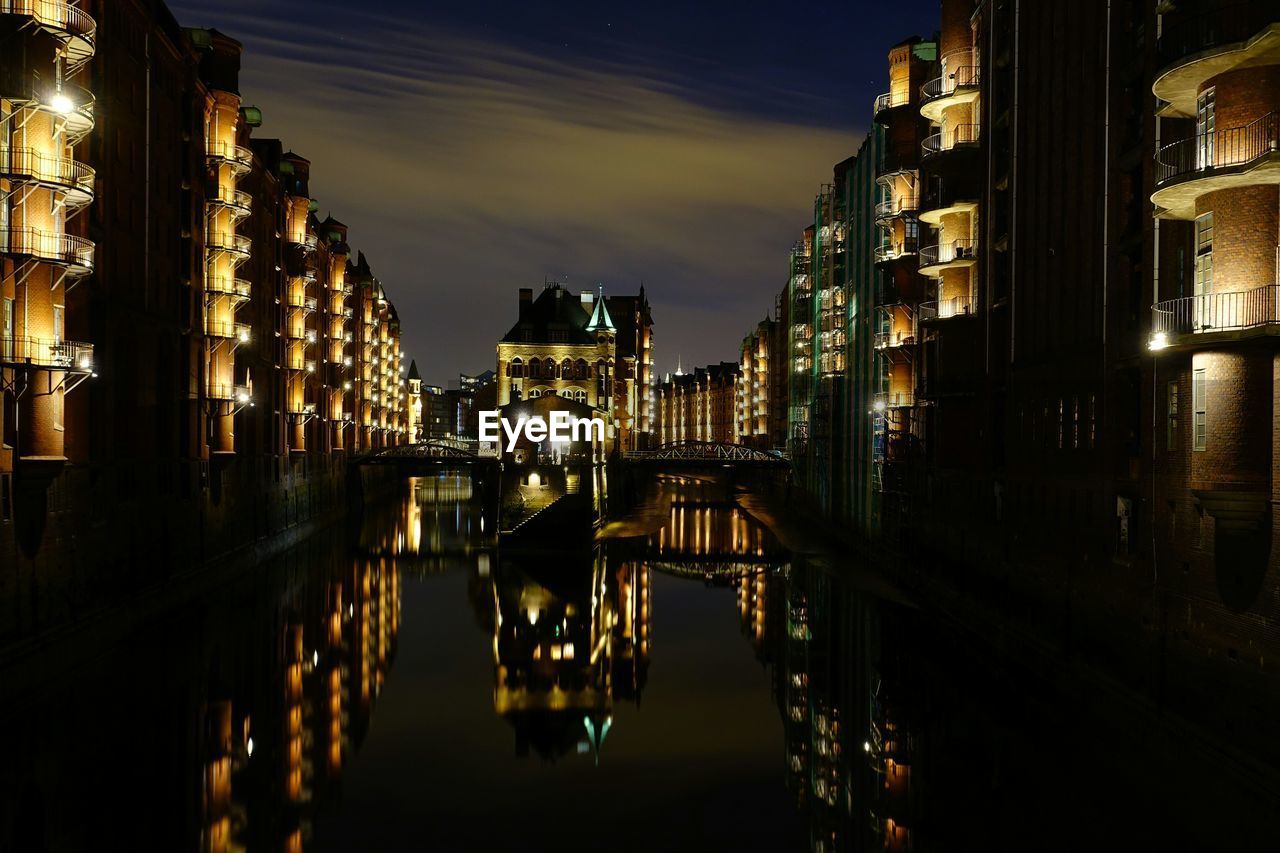 Canal amidst illuminated buildings against sky at night