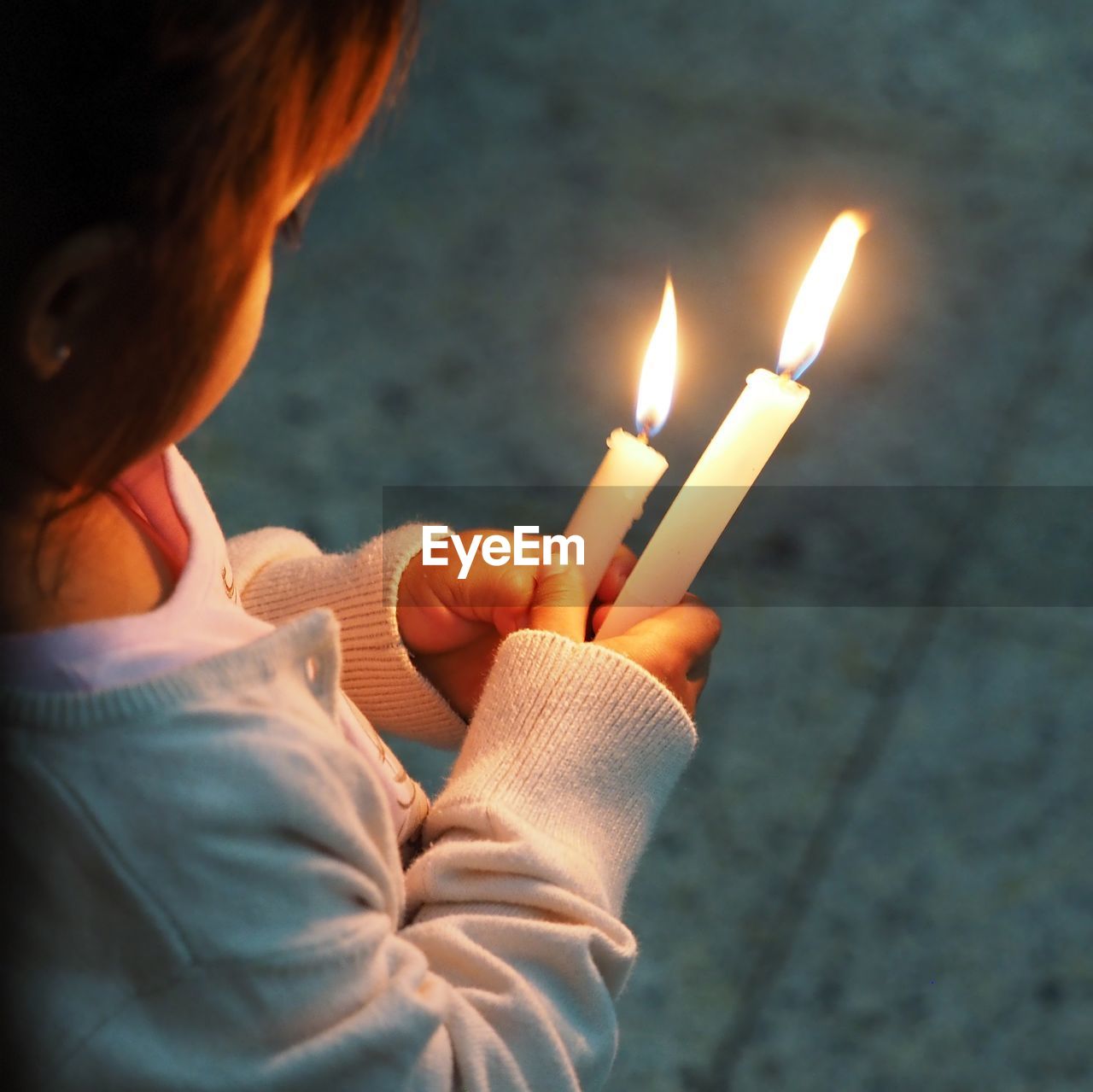 High angle view of girl holding illuminated candles on footpath