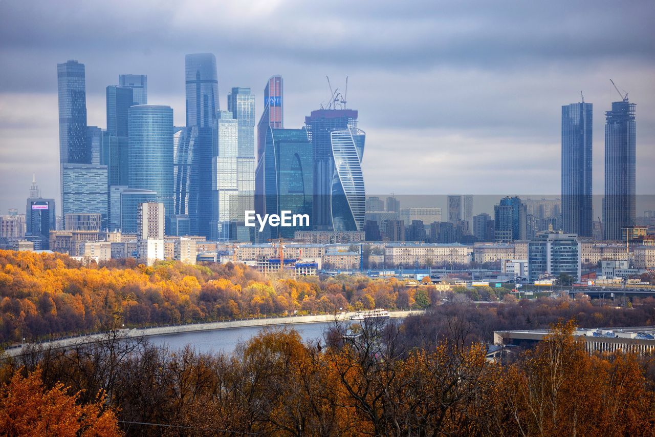 Modern buildings in city against sky during autumn