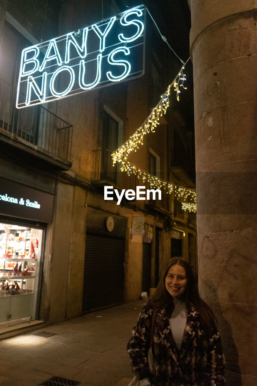 architecture, night, one person, city, text, illuminated, adult, building exterior, communication, built structure, portrait, sign, travel destinations, city life, western script, street, looking at camera, women, travel, building