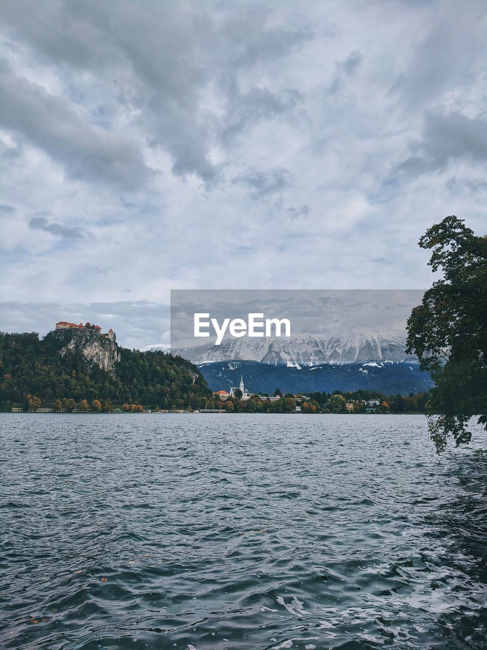 Scenic view of lake bled against cloudy sky.