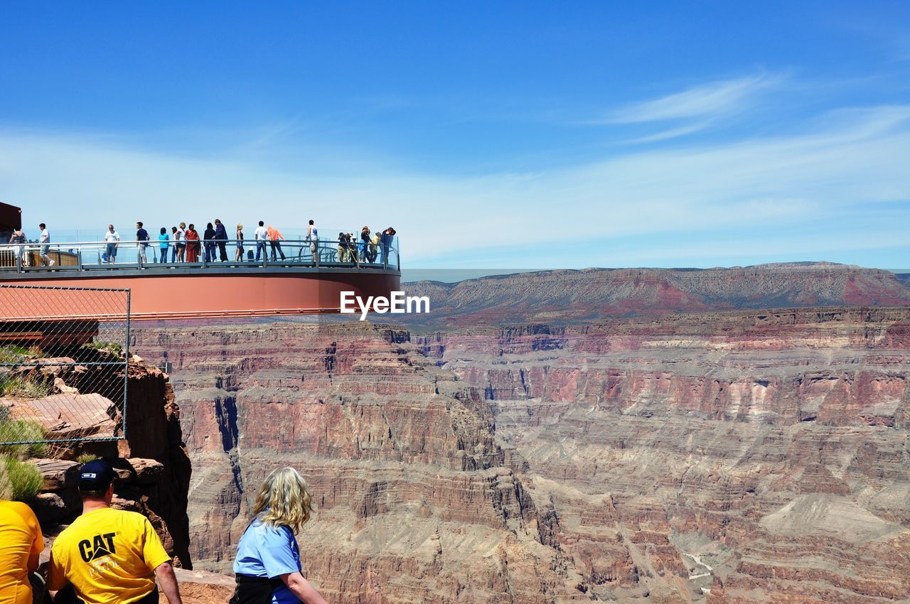 PEOPLE ON ROCK LOOKING AT VIEW OF A CITY