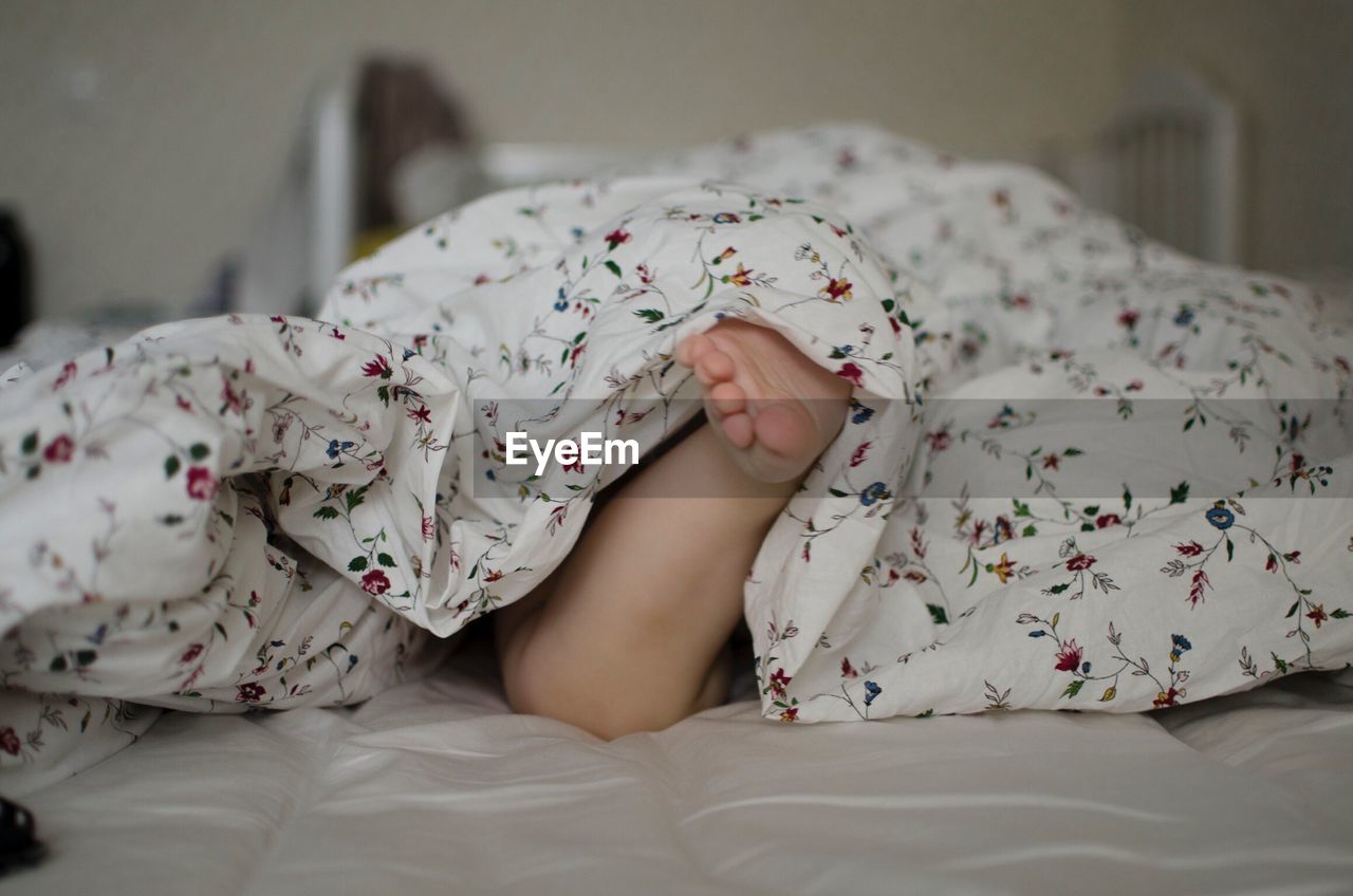 Low section of baby sleeping on bed