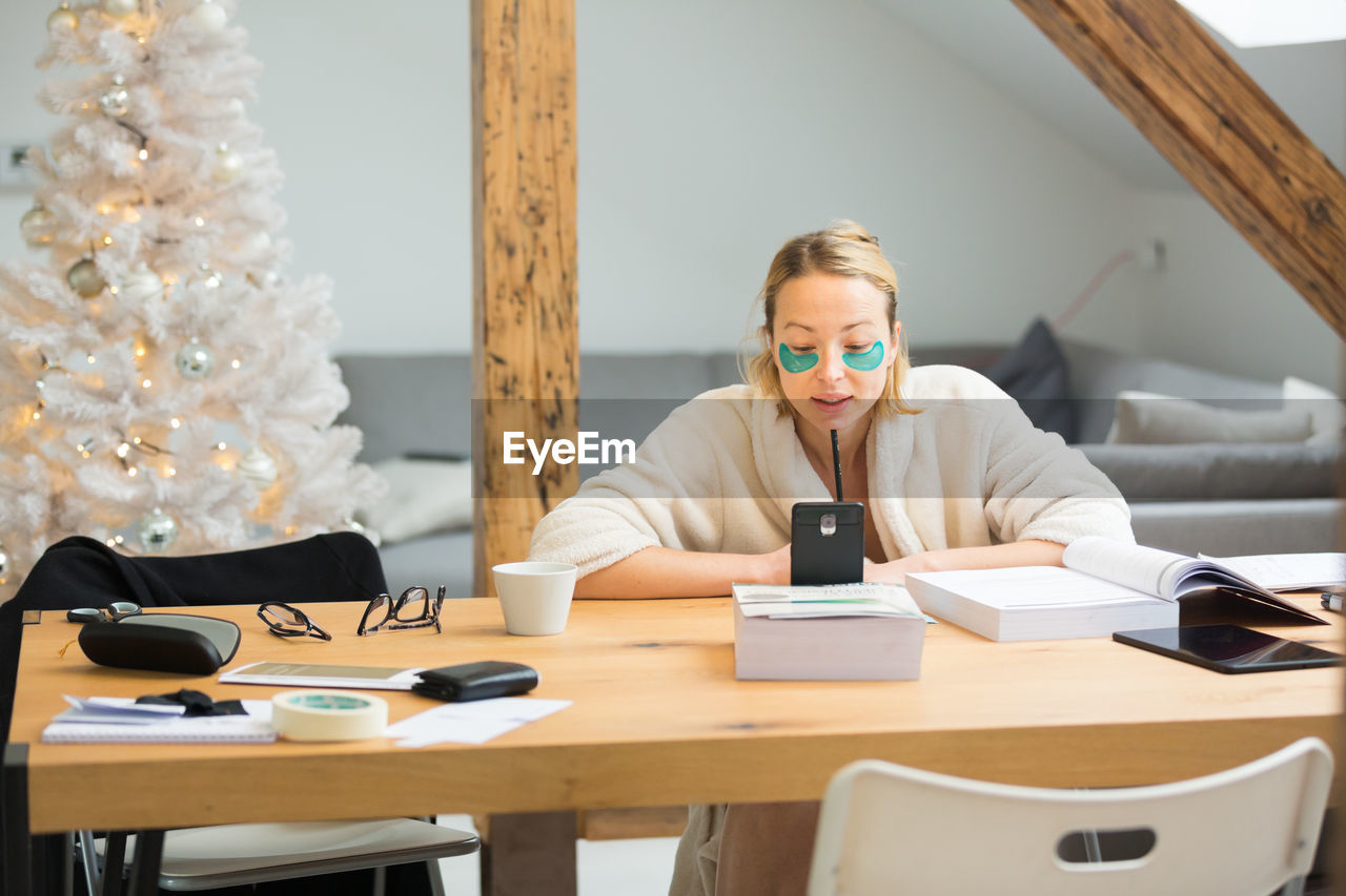 Businesswoman working at home by christmas tree