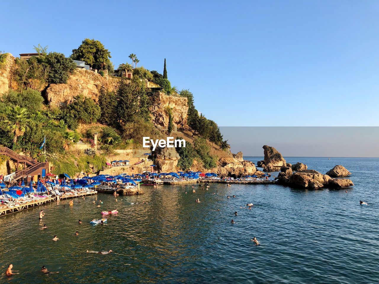 Group of people swimming in sea by mountain