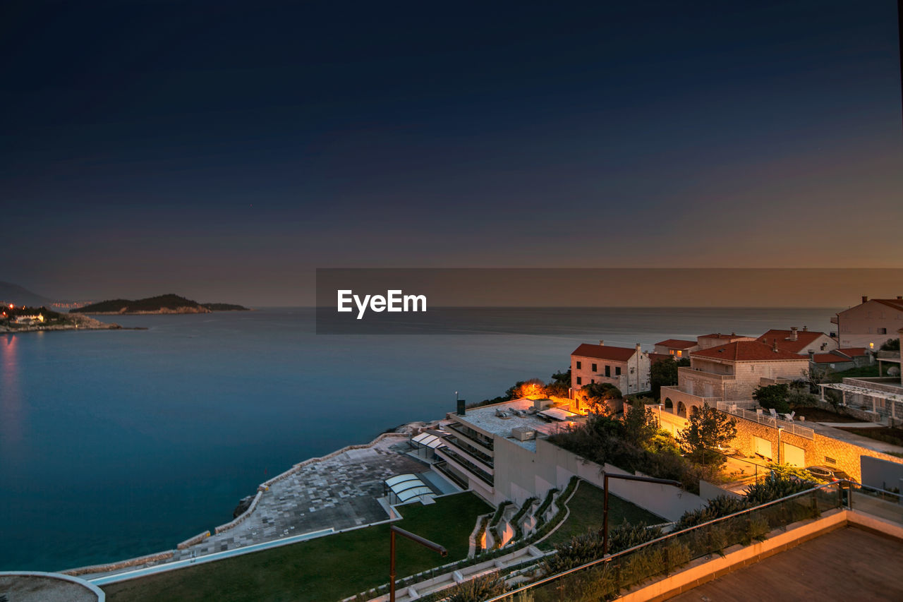 High angle view of buildings by sea against sky during sunset