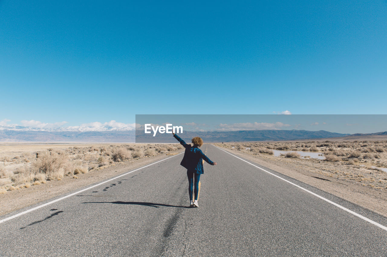 Woman standing on road against clear sky