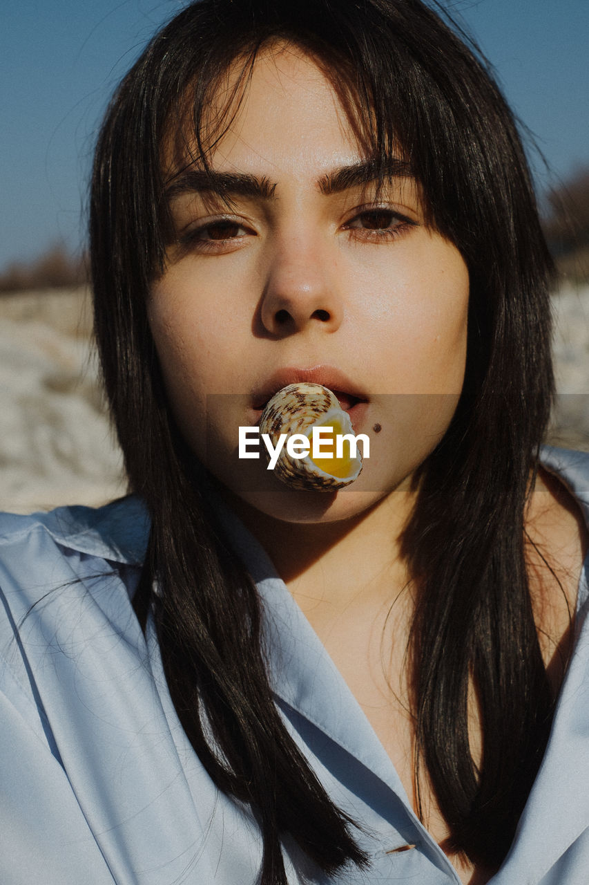 CLOSE-UP PORTRAIT OF A YOUNG WOMAN EATING FOOD