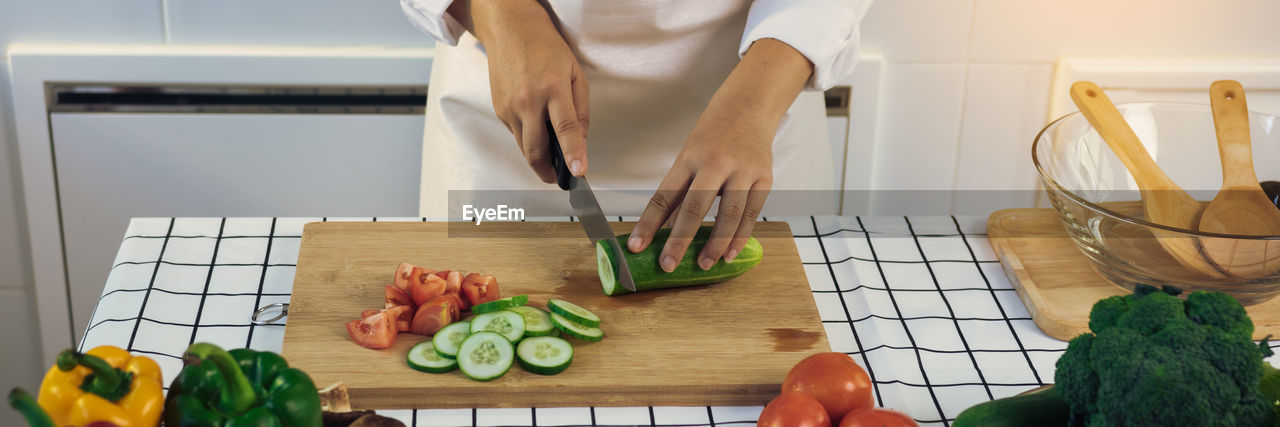 MIDSECTION OF WOMAN PREPARING FOOD AT KITCHEN