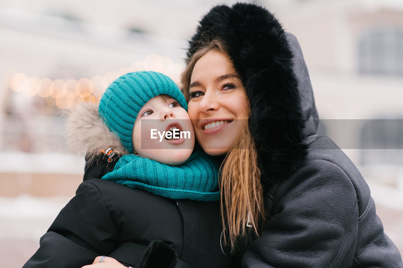 Happy mom and boy child are smiling at the camera in a snowy environment