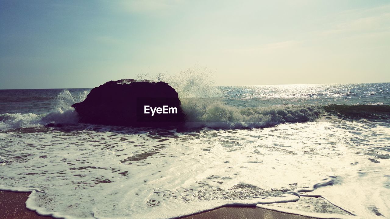 REAR VIEW OF MAN RELAXING AT BEACH