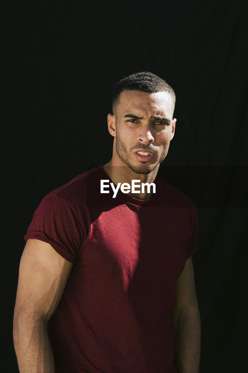 Portrait of young african american against black backdrop