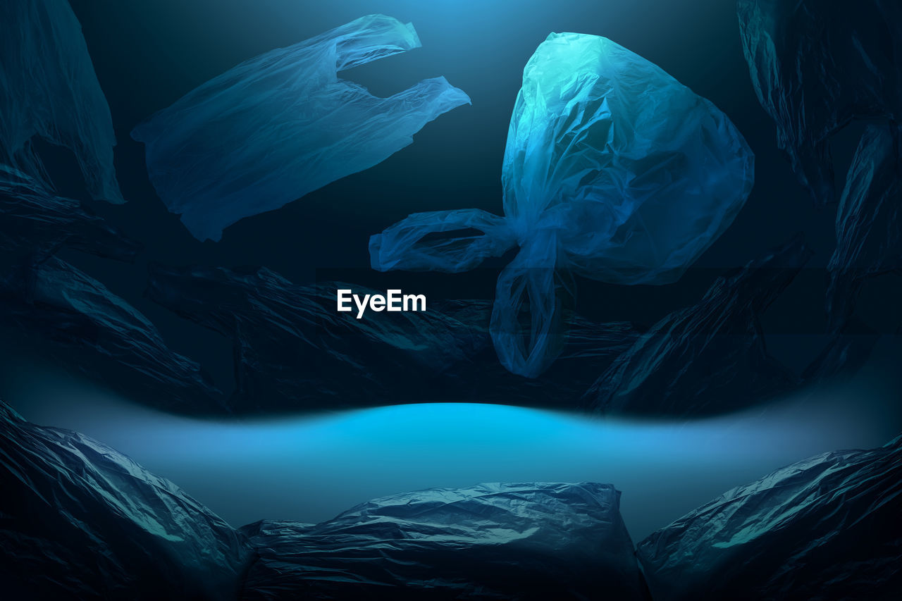 Creative background of single-use plastic bags floating in deep blue sea or ocean