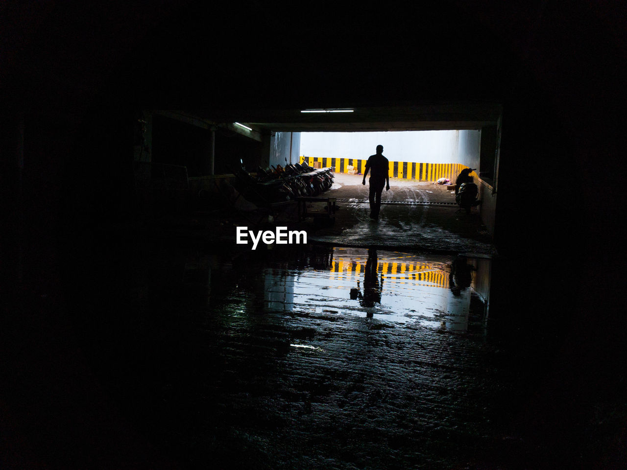 Silhouette man walking at underpass