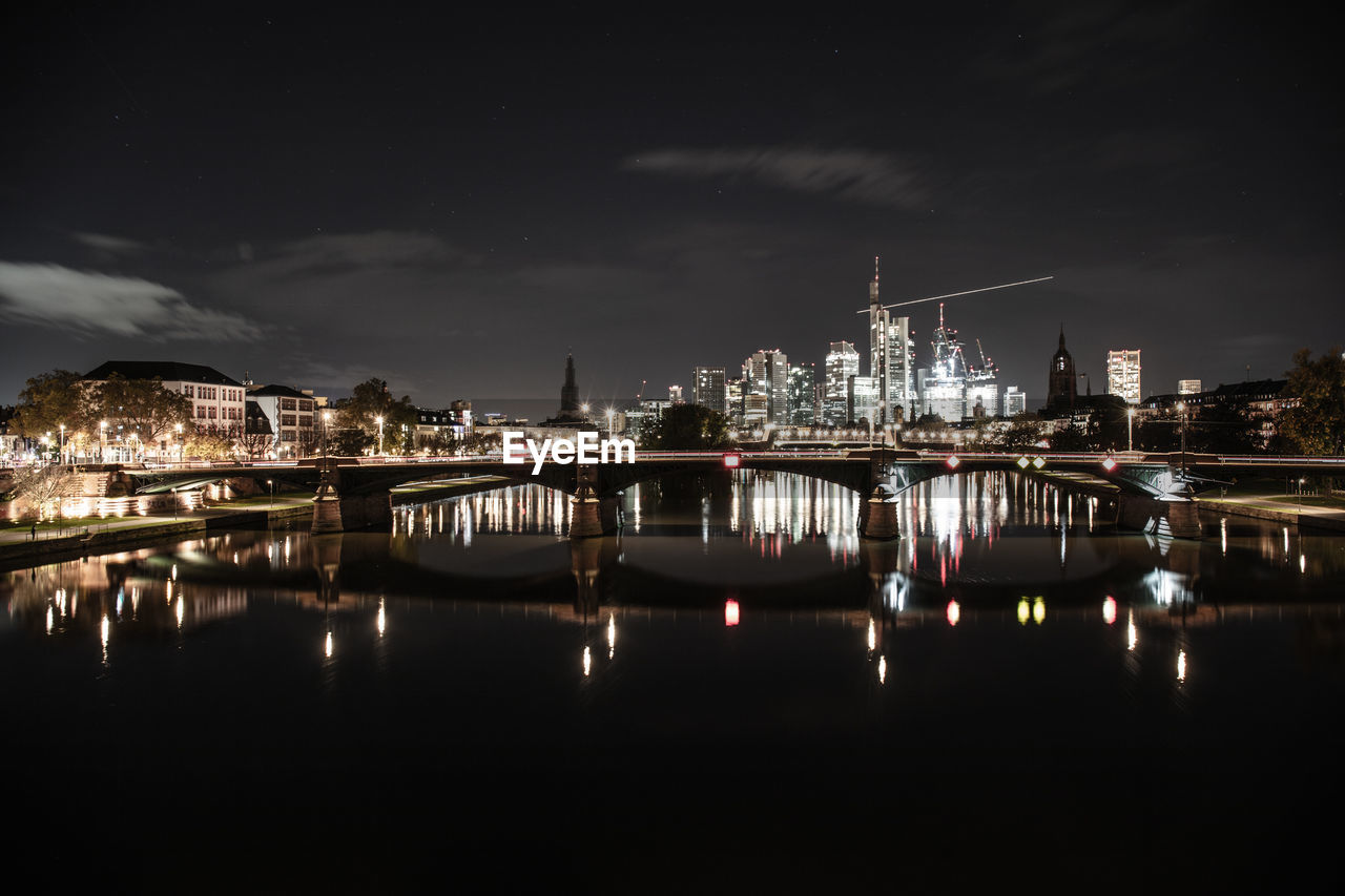 illuminated bridge over river in city at night